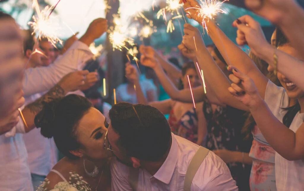 couple just married kissing with people who have sparklers around them