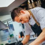 Chef in apron and gloves carefully preparing food